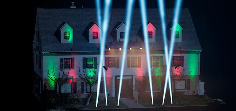 The show house washed in red and green light with white searchlight beams cutting the night sky
